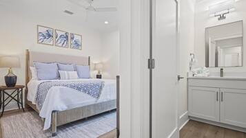 A bedroom with a bed, bedside tables, a ceiling fan, and artwork on the wall.