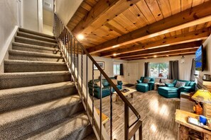 A staircase leading to a living area with a wooden ceiling and a view of the outdoors.