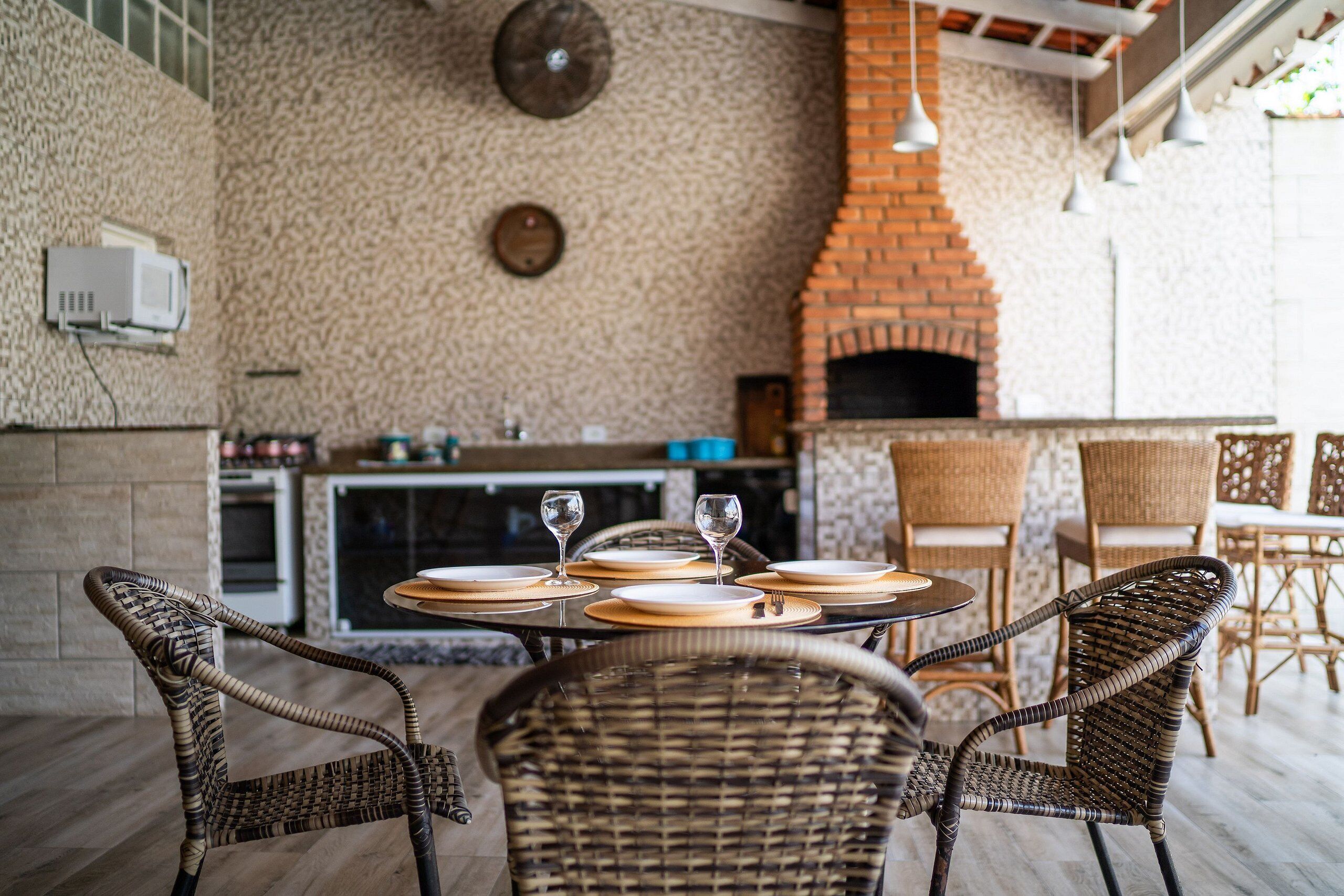 Un espace extérieur aménagé pour les repas, avec des chaises en osier et un four en briques.