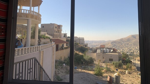 A view from a window overlooking a cityscape with buildings and hills. - Paradise Tree  (Wadi Musa)