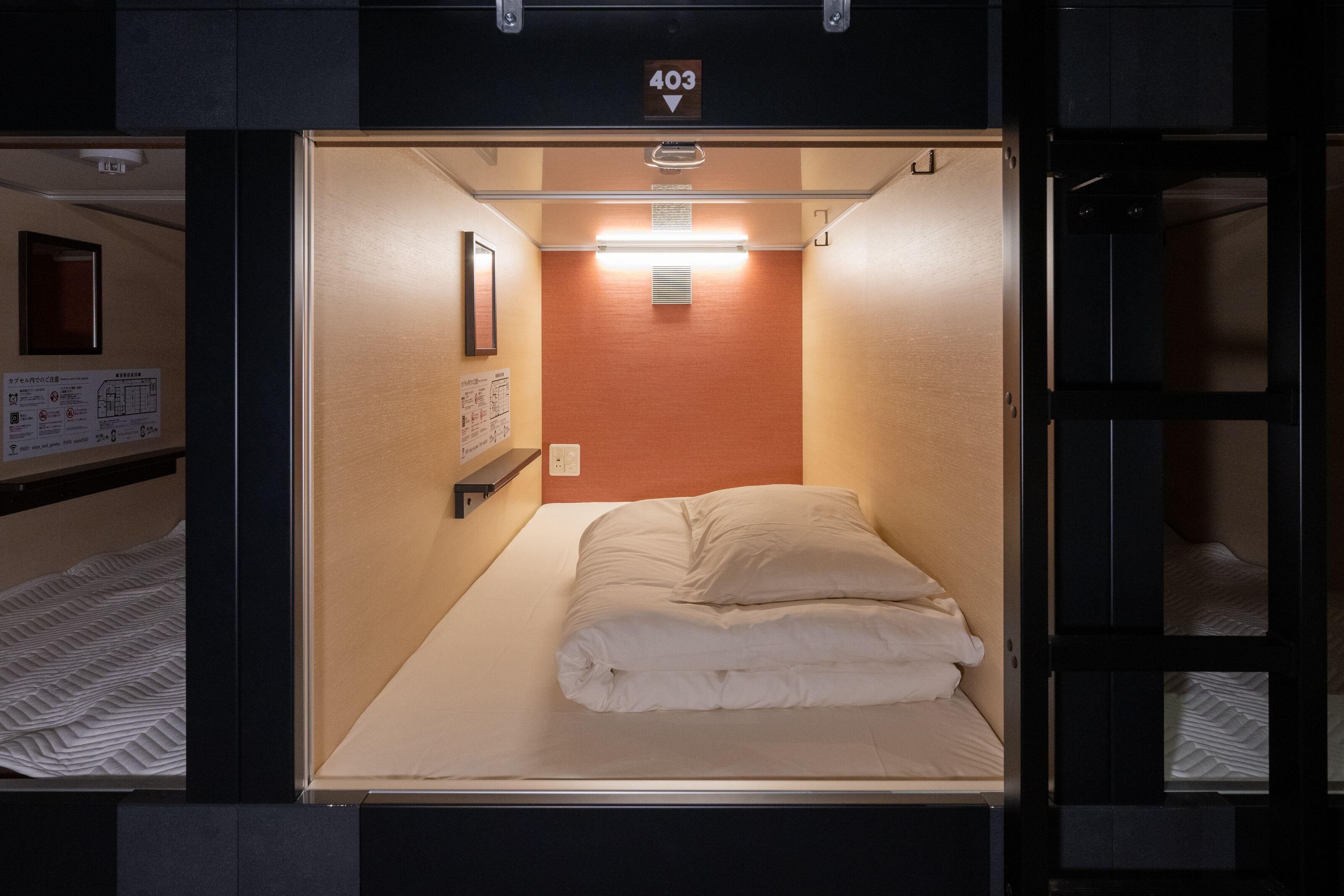 A compact hotel room with a single bed, a small bedside table, and a wall-mounted light fixture.