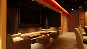 Un interior moderno con una zona de estar que incluye sofás, otomanas, un televisor de pantalla plana grande y un revestimiento de pared de madera.