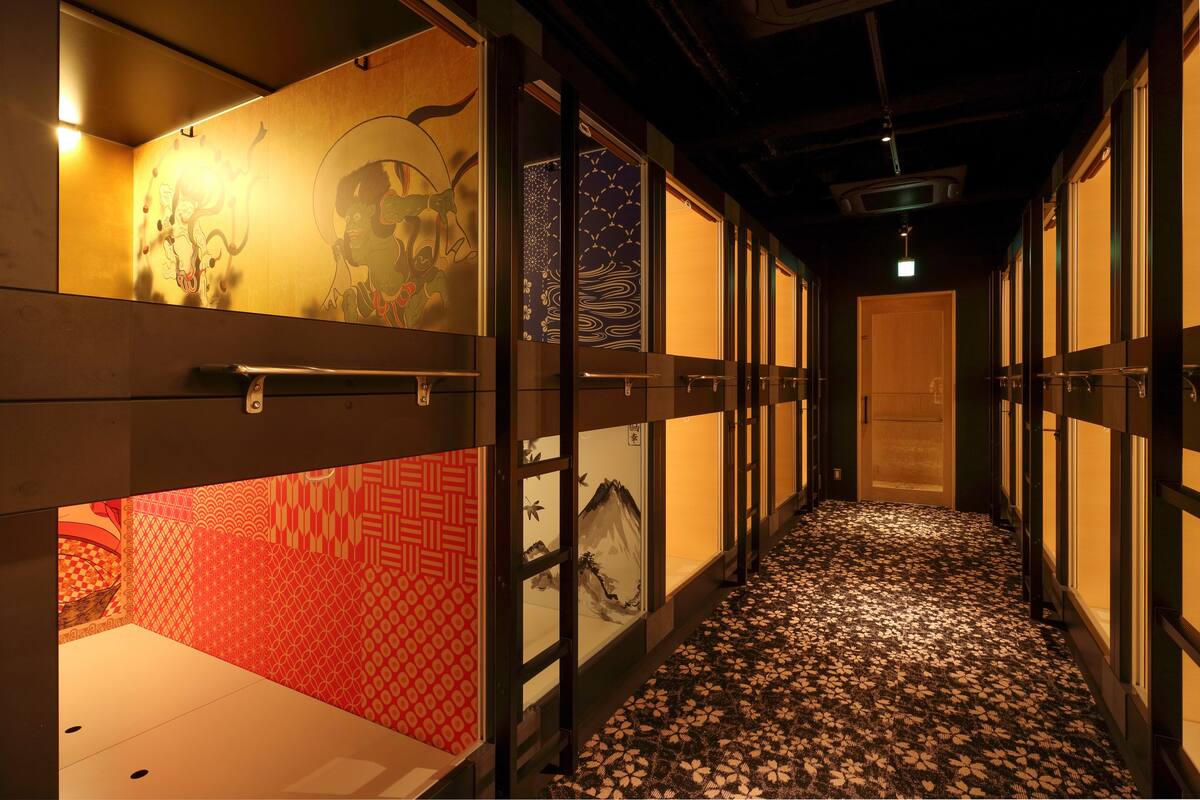 A corridor with traditional Japanese sliding doors, patterned wallpaper, and a patterned carpet.
