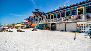 Ein Gebäude direkt am Strand mit farbenfrohen Außenwänden, mehreren Balkonen und Außenbereichen mit Sonnenschirmen.