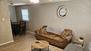 A living room with a brown sofa, a grey sofa, a round coffee table, and a dining area with a table and chairs. - 5 minutes from Tech/UMC // book a quaint 3 bedroom home w/wifi and laundry (Lubbock)