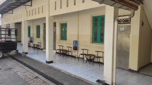A building with a covered outdoor seating area, a water dispenser, and a trash bin. - OYO 93048 Hotel Puri Mandiri (Kutoarjo)