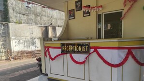 A reception area with a sign labeled "RECEPTIONIST," a tiled floor, and a concrete wall in the background. - OYO 93048 Hotel Puri Mandiri (Kutoarjo)
