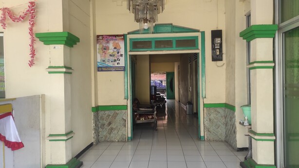 A hallway with a green and white color scheme, a chandelier, and a poster on the wall. - OYO 93048 Hotel Puri Mandiri (Kutoarjo)