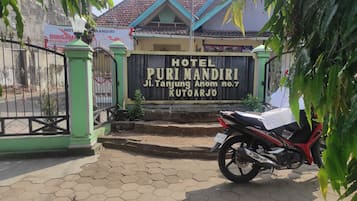 A hotel entrance with a sign reading "HOTEL PURI MANDIRI Ji. Tanjung Anom no.7 KUTOARJO".