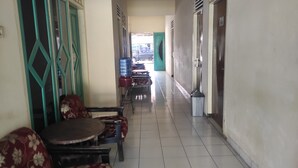 A corridor with seating arrangements, a water dispenser, and a trash bin. - OYO 93048 Hotel Puri Mandiri (Kutoarjo)