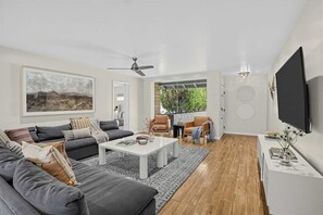 A modern living room with a sofa, coffee table, and a TV mounted on the wall. - Indigo Oasis, Pool, Sleeps 18 (Phoenix)