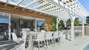 An outdoor patio with a pool, a wooden deck, and a pergola structure.