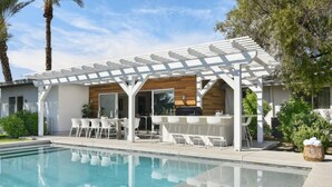 A poolside area with a pergola, outdoor seating, and a bar.
