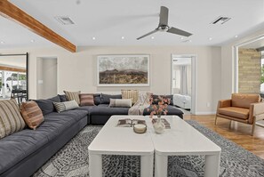 Un salon moderne avec un canapé d’angle, une table basse et un ventilateur de plafond.