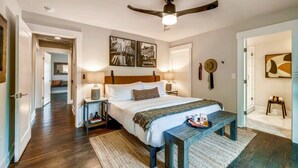 Ein Schlafzimmer mit einem großen Bett, Nachttischen, einem Deckenventilator und Kunstwerken an den Wänden.