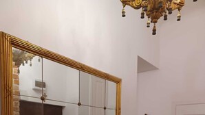 A room with a large mirror, a wooden bench, a door, and a chandelier. - Luxury Living Kopernik (Warszawa)