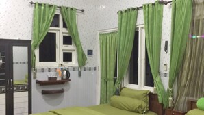 A room with two beds, green curtains, an air conditioning unit, and a small shelf with toiletries. - OYO Life 93055 Fathin Hotel (Sangkapura)