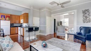 A modern living room with a marble coffee table, a sofa, and a blue leather chair. - Historic 1800's Condo, Forsyth | Dog-Friendly! (Savannah)