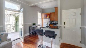 A modern kitchen with a central island, bar stools, and a dining area with a white sofa. - Historic 1800's Condo, Forsyth | Dog-Friendly! (Savannah)