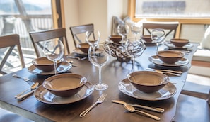 Une table à manger dressée avec des bols marron, des verres à vin et des couverts.