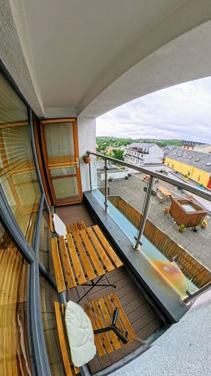 A balcony with a wooden bench, a small table, and a view of a residential area. - 12 Courthouse Square Apt with Parking (Clifden)