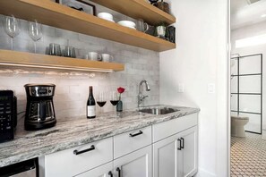 Una cocina moderna con armarios blancos, encimera de mármol y una cafetera.