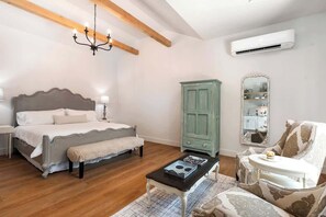 A bedroom with a bed, bedside table, bench, dresser, chair, and a small table with a book.
