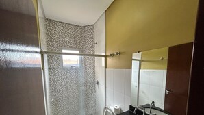 Un baño con cabina de ducha de vidrio, inodoro, lavamanos y espejo.