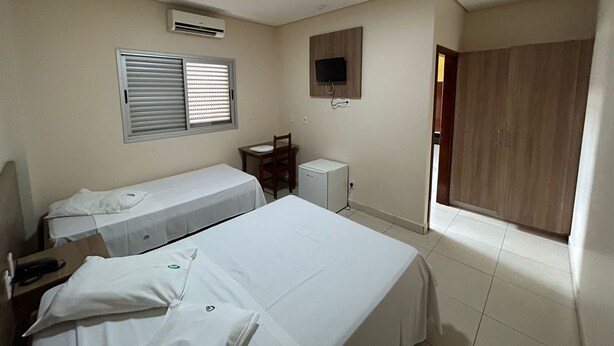 Habitación de hotel con dos camas, un escritorio, un televisor y un armario.