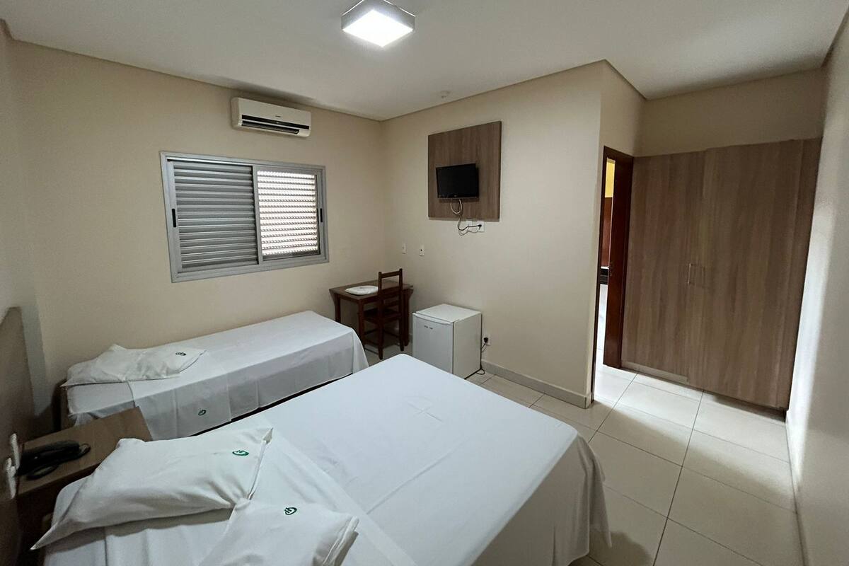 A hotel room with two beds, a desk, a TV, and a wardrobe.