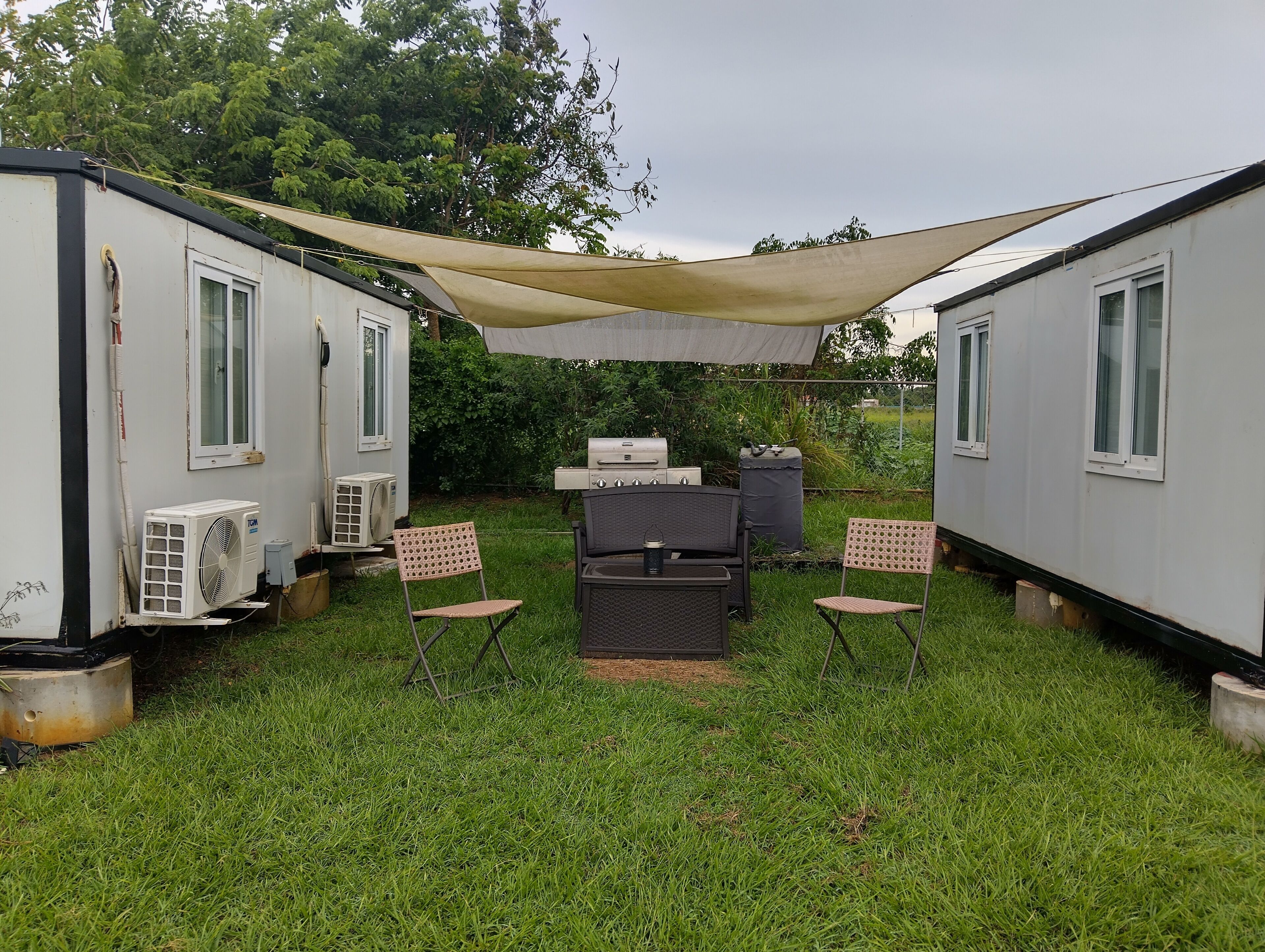 A small outdoor area with a grill, chairs, and a fan.