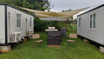 A small outdoor area with a grill, chairs, and a fan.