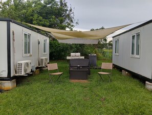 A small outdoor area with a grill, chairs, and a fan.