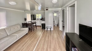 Interior moderno de una caravana con sala de estar, kitchenette y comedor.