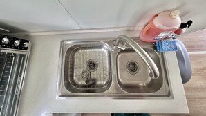 Un lavamanos con grifo, una botella de detergente y una esponja.