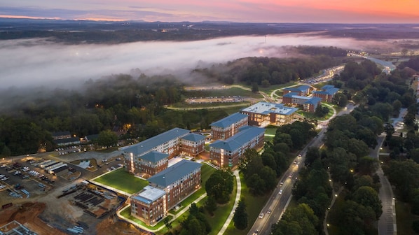 An aerial view of a campus with multiple brick buildings, roads, and a parking lot.