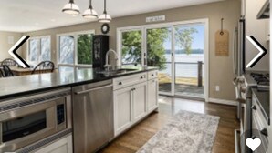 A modern kitchen with stainless steel appliances, a large island, pendant lighting, and a view of the outdoors.