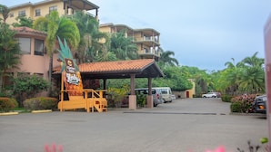 A hotel entrance with a covered waiting area, a sign for Clarion Suites, and parked vehicles.
