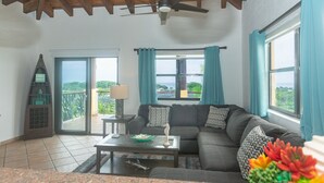 A living room with a dark gray sofa, a coffee table, and a view of the outdoors through large windows.