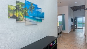 A hotel lobby with a white textured wall, a black console table, and a view of the ocean through a glass door.