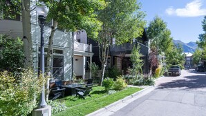 A residential street with houses, a lawn, and a parked car.
