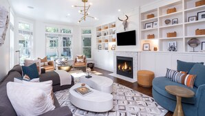 A modern living room with a fireplace, white shelving with decorative items, and comfortable seating.