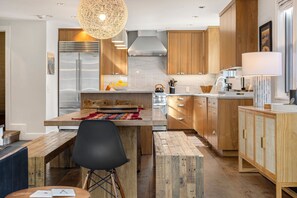 Eine moderne Küche mit Holzschränken, einem Edelstahlkühlschrank und einer zentralen Kochinsel mit Sitzgelegenheiten.