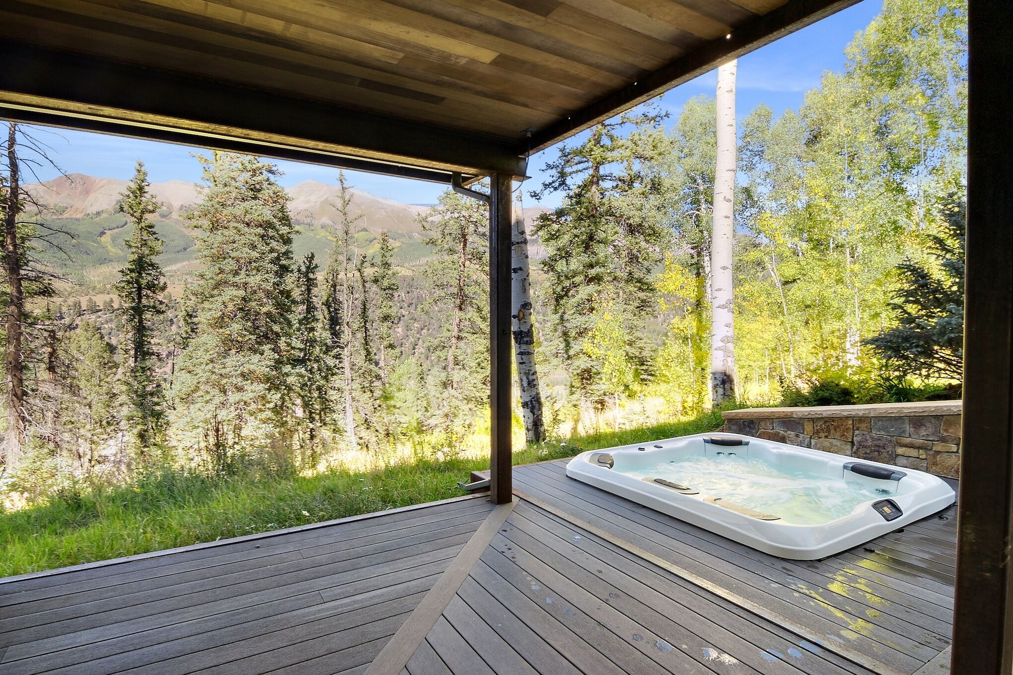 A hot tub on a wooden deck with a mountain view.