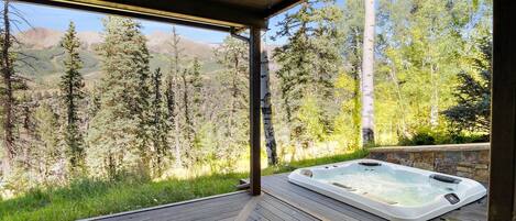 A hot tub on a wooden deck with a mountain view.