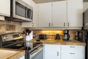 A modern kitchen with stainless steel appliances, a microwave, a coffee maker, and a toaster. - Village Loft 31 At Park City Mountain 2 Bedroom Condo by RedAwning (Park City)