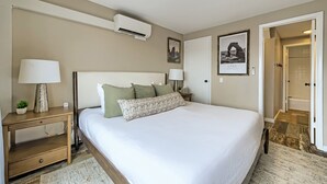 A hotel room with a bed, bedside tables, a lamp, an air conditioning unit, and a framed picture on the wall. - Village Loft 31 At Park City Mountain 2 Bedroom Condo by RedAwning (Park City)