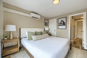 A hotel room with a bed, bedside tables, a lamp, an air conditioning unit, and a framed picture on the wall. - Village Loft 31 At Park City Mountain 2 Bedroom Condo by RedAwning (Park City)