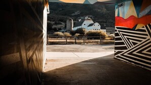 A rural landscape with a white barn and silo, surrounded by fences and vegetation, viewed through a geometric patterned structure. - Village Loft 31 At Park City Mountain 2 Bedroom Condo by RedAwning (Park City)