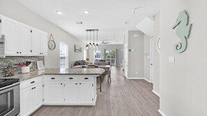 A modern kitchen with white cabinetry, a granite countertop, and a central island. - ☀️Short Walk to Beach-Pet Friendly-4 Bikes-Bluebonnet by the Beach☀️ (Santa Rosa Beach)